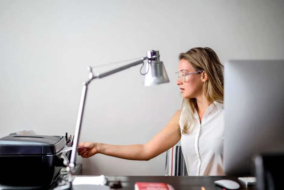 Office worker retrieving a printed page from a desktop printer