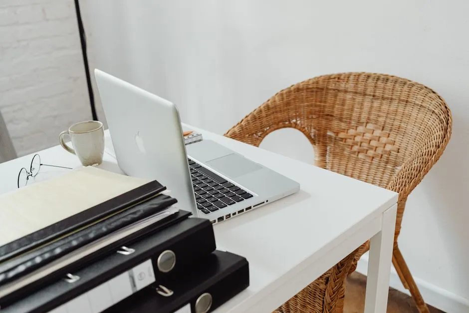 Desk with a laptop, reading glasses, and paper document binders